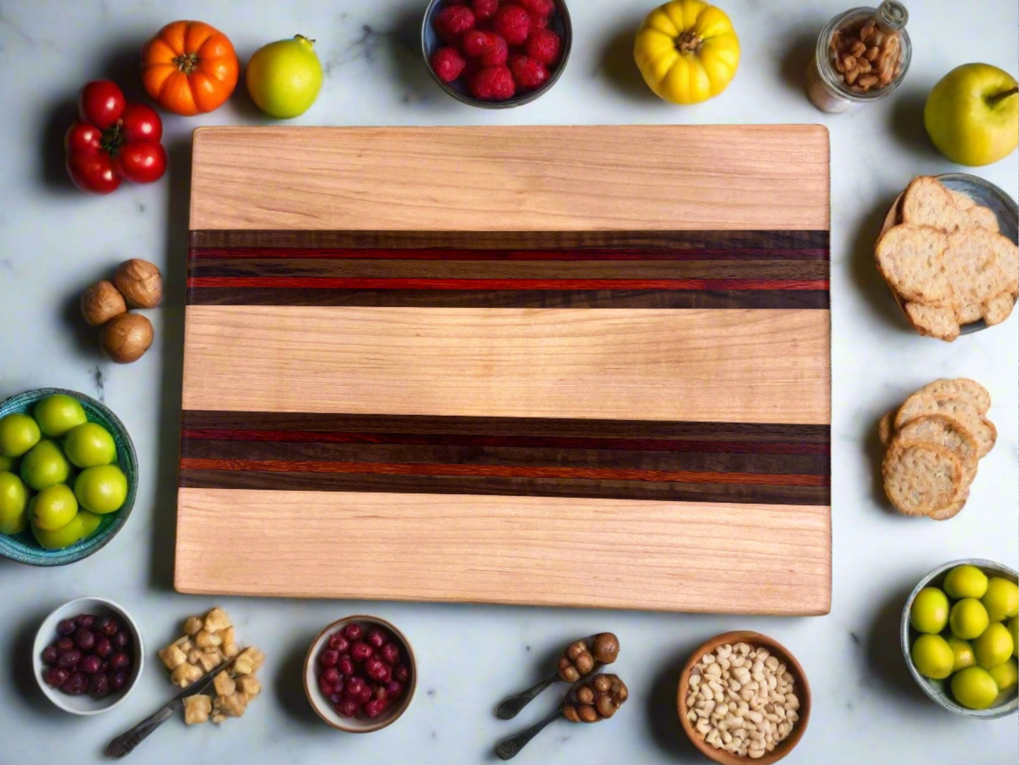 Artisan Board #3 by Wet Nose Woodworks, featuring dark stripes, sits on marble surrounded by fruits, nuts, bread slices, and tomatoes. The colorful display showcases the fine craftsmanship of this artisan board.