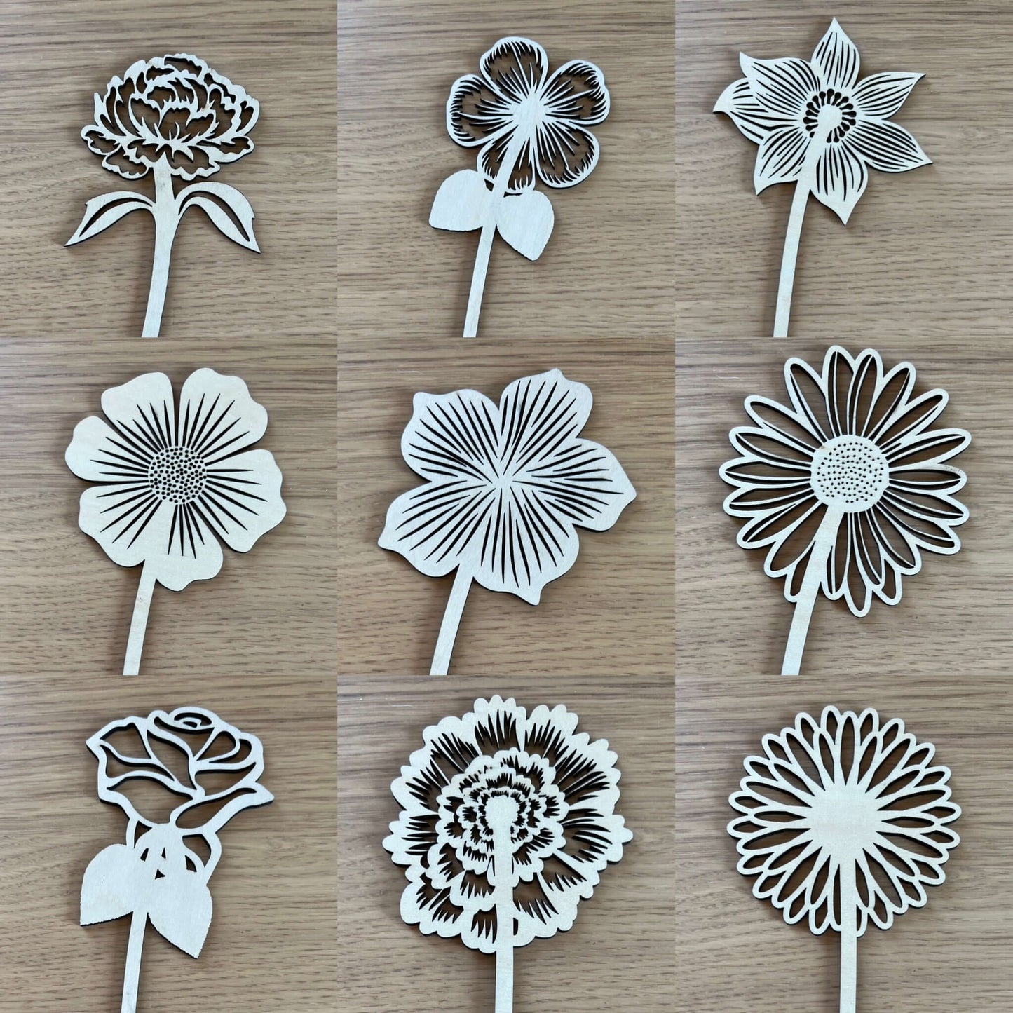 Nine Birth Month Wooden Flowers by Wet Nose Woodworks, each uniquely designed with detailed petals and a graceful stem, are arranged in a 3x3 grid on a light wood surface for a beautifully rustic display.
