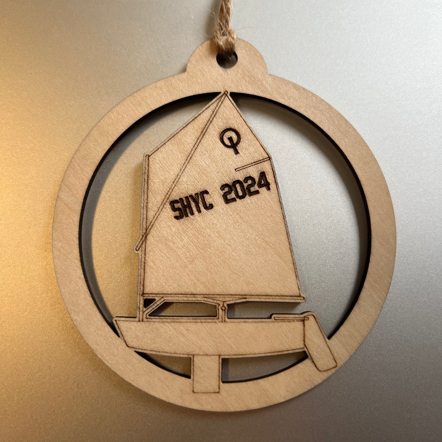 Wooden ornament with sailboat design and 'SHYC 2024' text on a neutral background