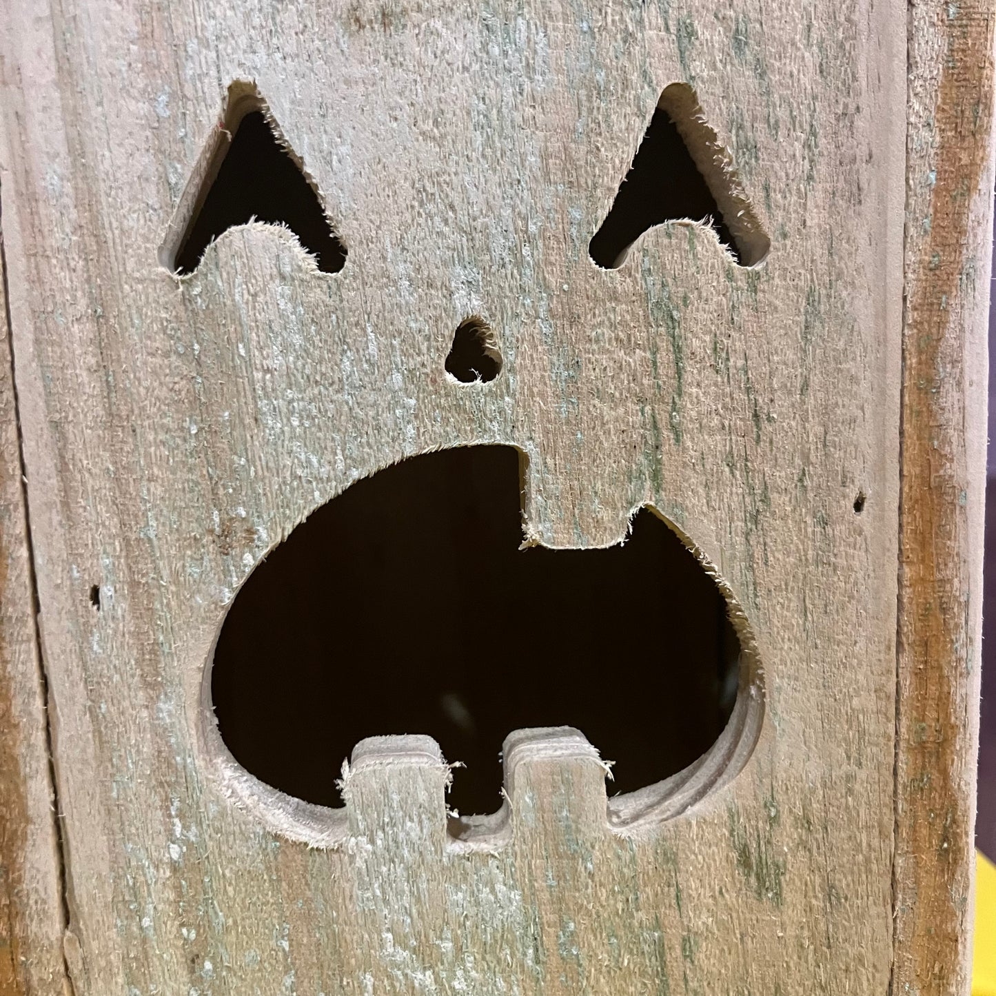 Six Wet Nose Woodworks Halloween lanterns with unique carved faces and slanted wooden lids, crafted from pressure-treated wood, are stacked in a pyramid against an orange background for festive Halloween decor.
