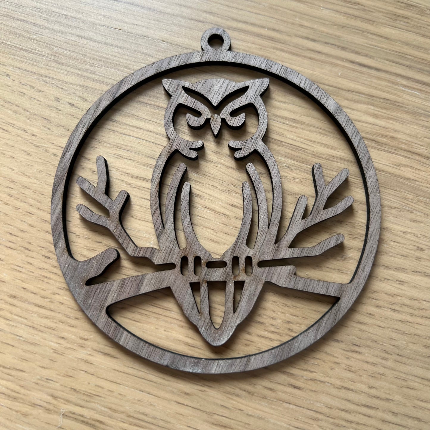 The Owl ornament by Wet Nose Woodworks is a decorative metal silhouette of an owl on a branch, perfect for hanging in your window as an eco-friendly rustic home accent.