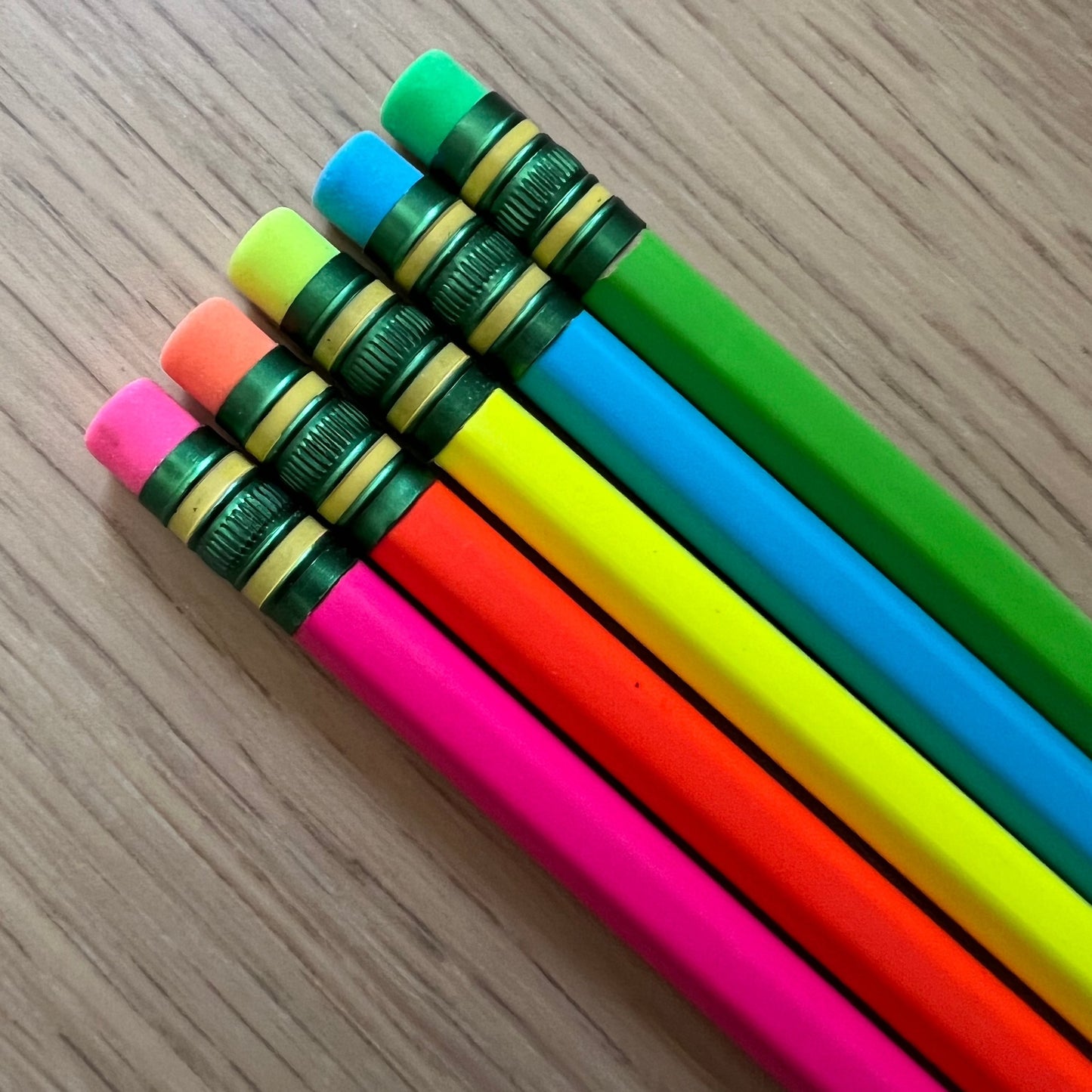 Three yellow Personalized Pencils by Wet Nose Woodworks, each with a green eraser and custom black text (GRACE CRAWFORD, WET NOSE WOODWORKS, TOMMY CRAWFORD), rest on a wooden surface—ideal for the new school year.