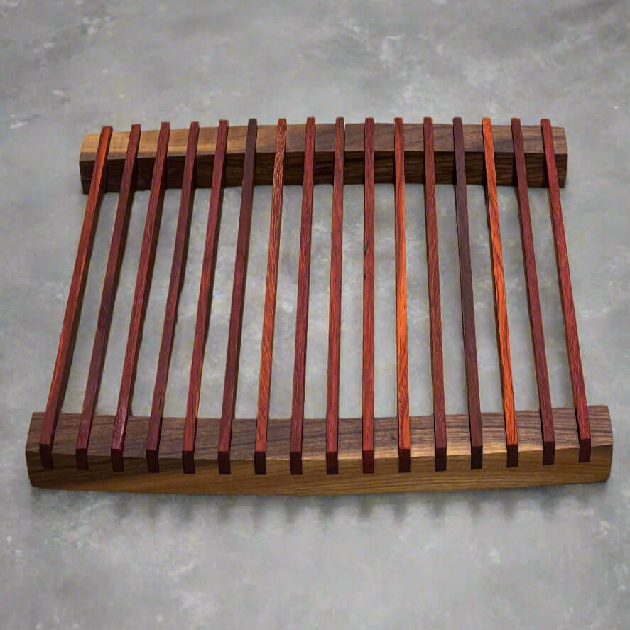 The Artisan Board #13 by Wet Nose Woodworks is a unique walnut and padauk trivet with parallel slats in brown and reddish tones—an elegant wooden design that protects your dining table.
