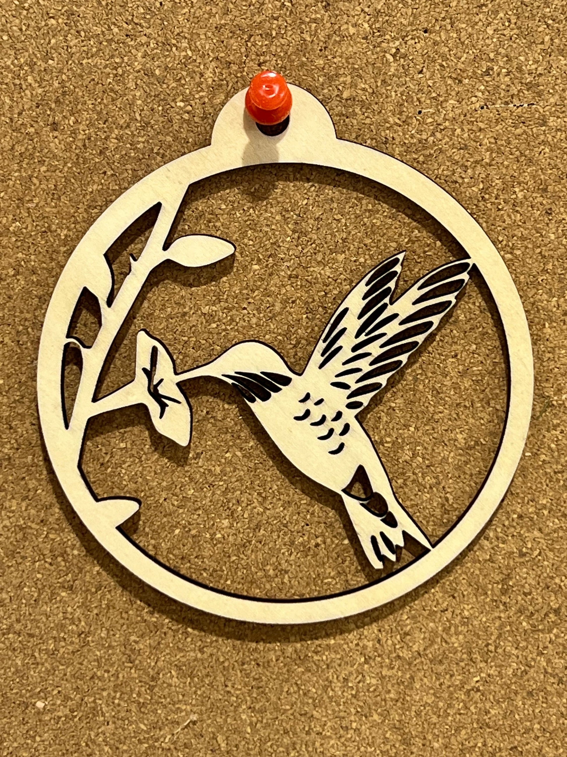 The Digital Hummingbird Ornament by Wet Nose Woodworks features a circular design of a hummingbird and flower, perfect as a DIY laser cut craft. Includes inspirational card files in PDF, SVG, and Lightburn formats—ideal for gifting and decor.