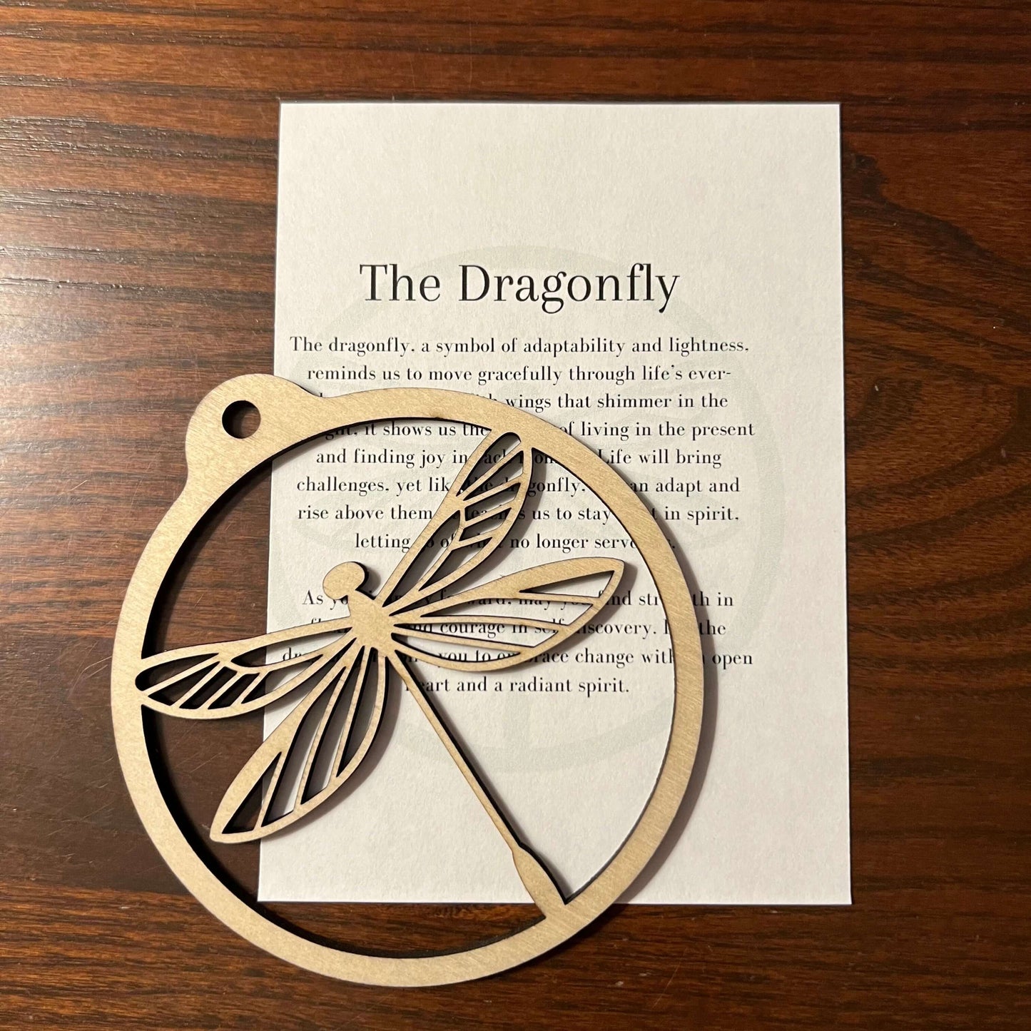 The Dragonfly Ornament by Wet Nose Woodworks is a handcrafted wooden piece on a card titled The Dragonfly, highlighting its symbolism of adaptability and lightness—a charming rustic accent for any home.
