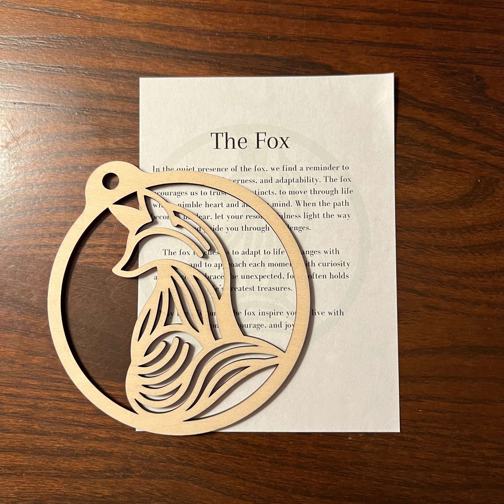 The Fox Ornament by Wet Nose Woodworks is a handcrafted wooden piece with swirling cut-out details, presented on a printed card titled The Fox with inspirational text—an eco-friendly home accent.