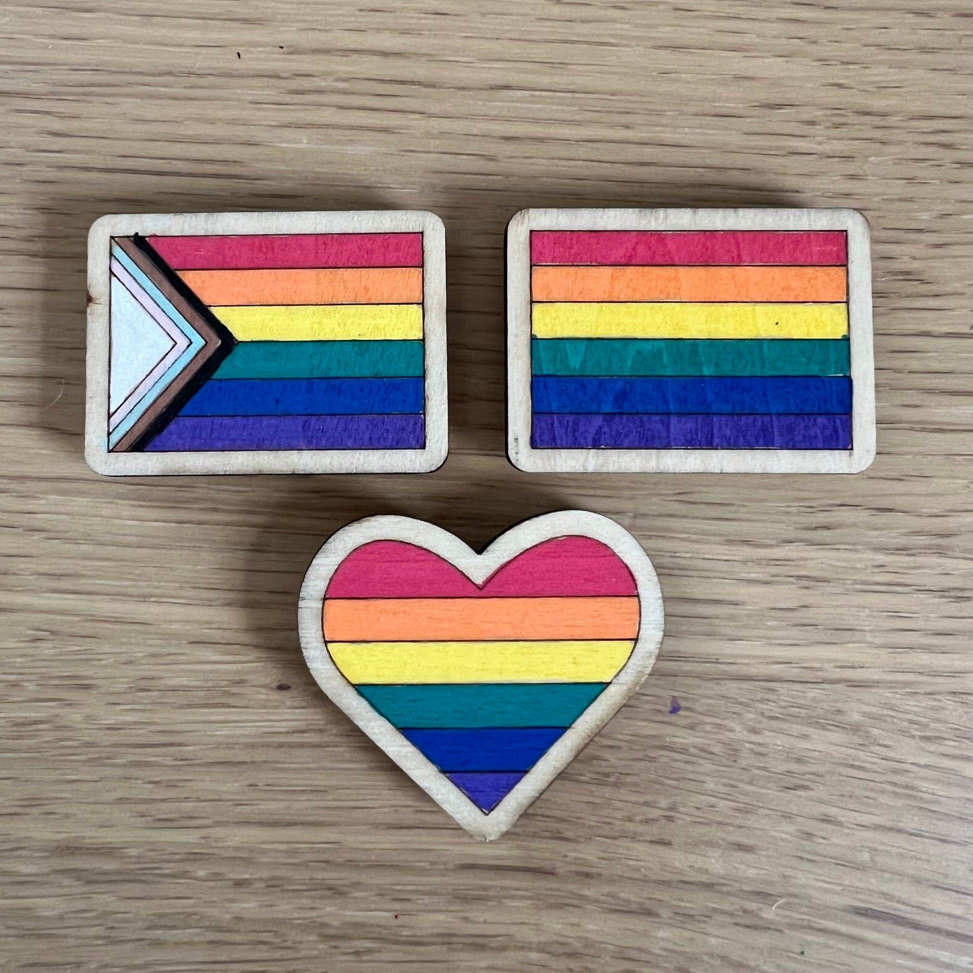 Hand-painted wooden magnet featuring a colorful rainbow Pride flag design on a wooden base.