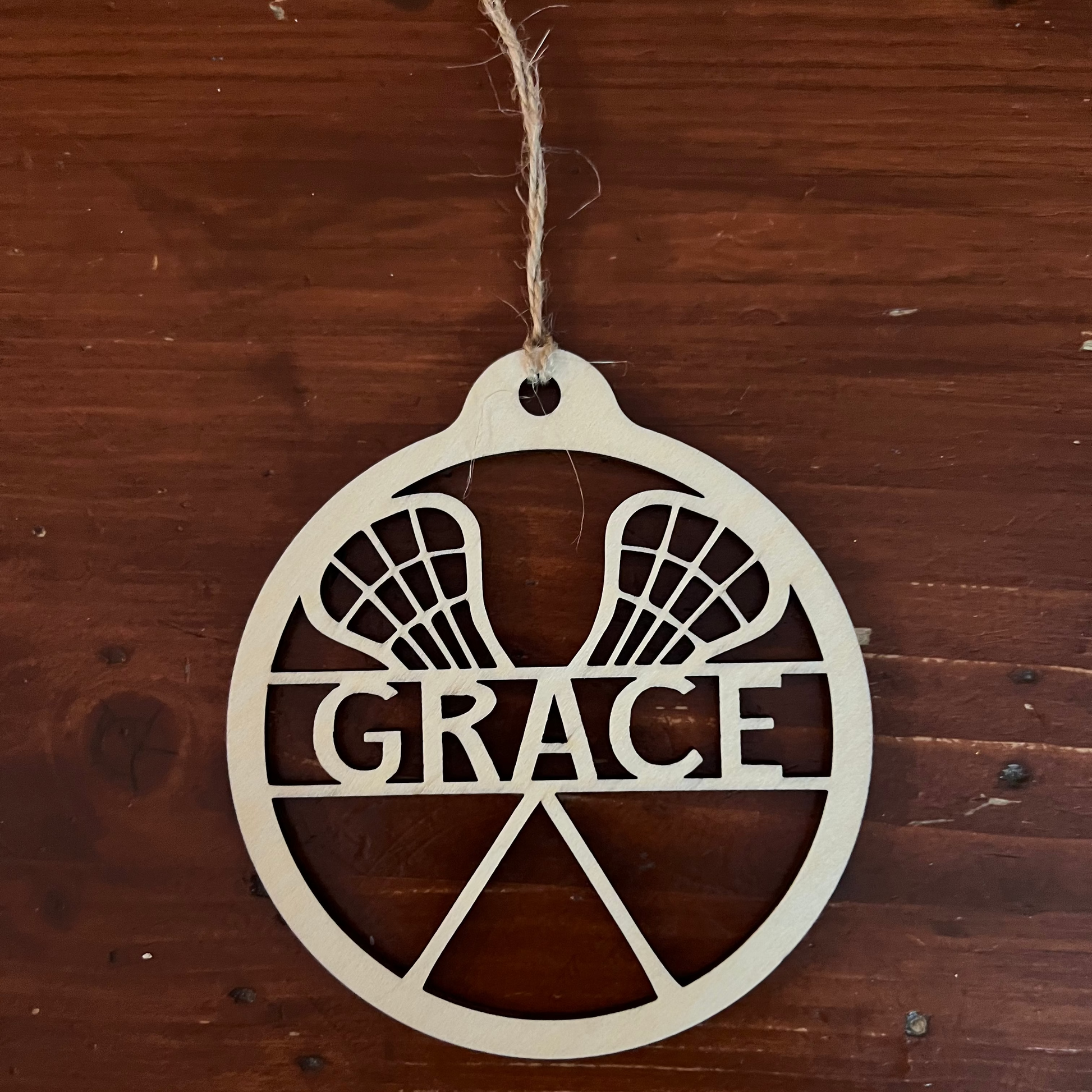 Decorative ornament with 'GRACE' on a wooden background with Lacrosse sticks