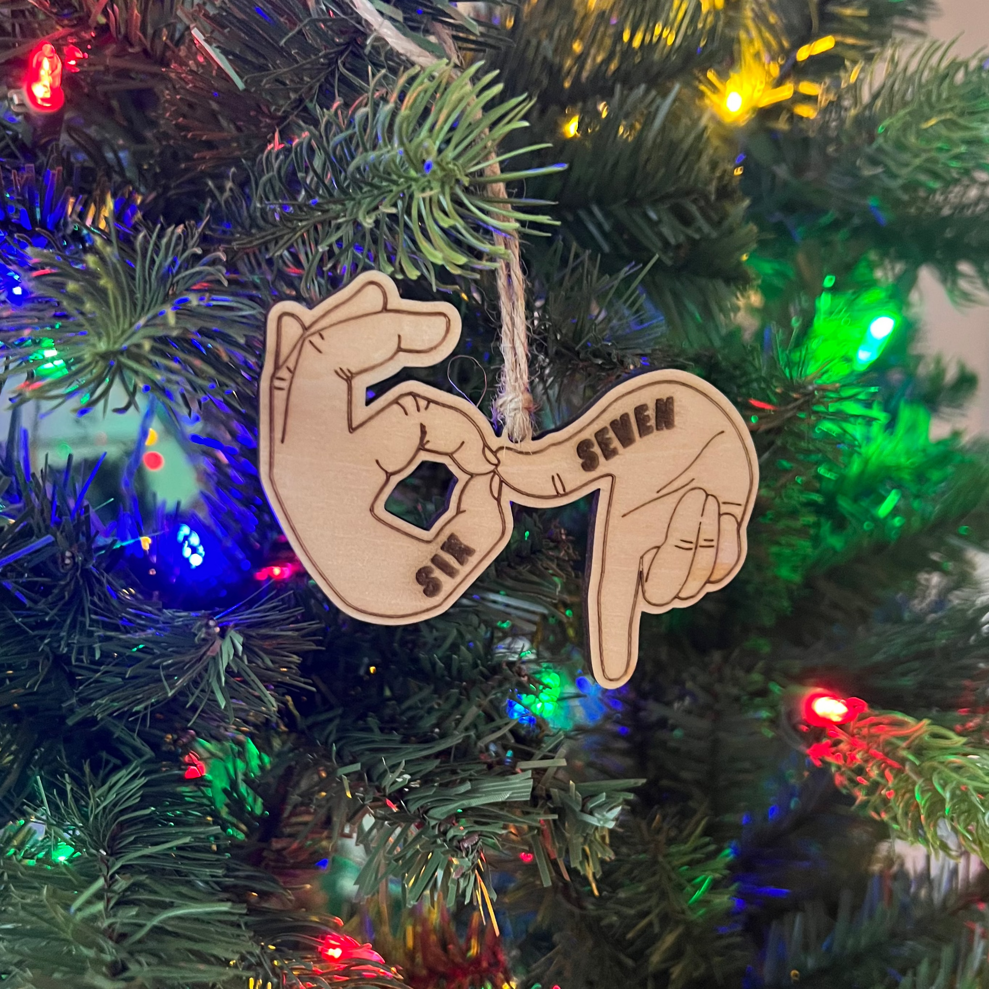 Decorative ornament with hand signs on a Christmas tree with colorful lights.