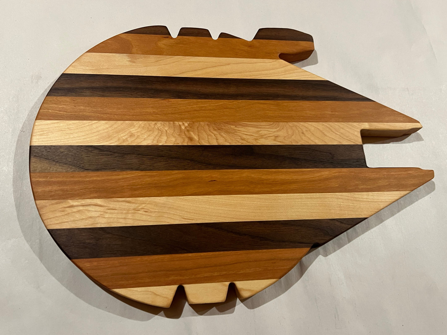 Wooden cutting board shaped like a spaceship on a light gray background
