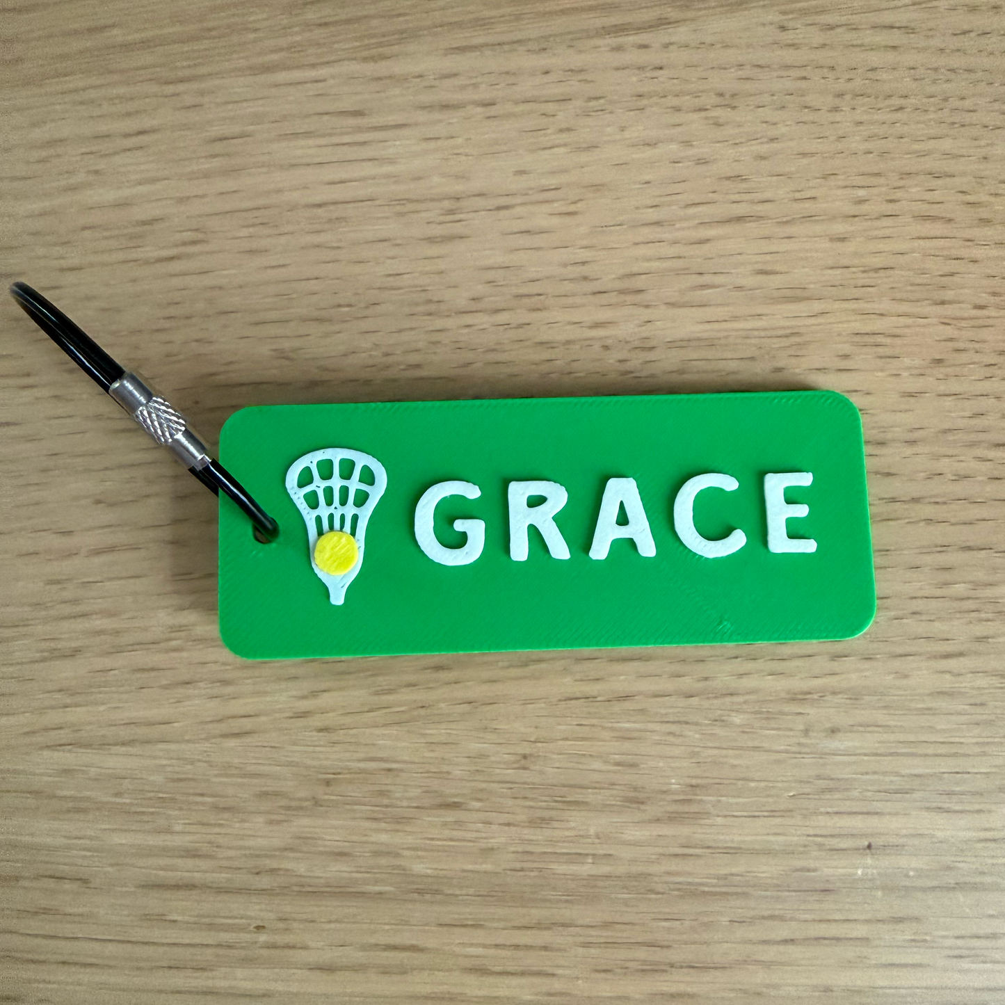 Green tag with 'GRACE' and a lacrosse stick logo on a wooden surface