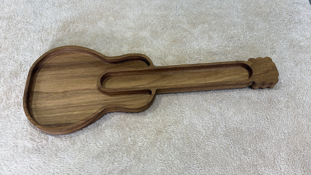 A wooden guitar-shaped tray with a carved headstock and soundhole detail, resting on a textured beige carpet.